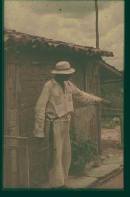 [Homem de branco na frente de uma casa]